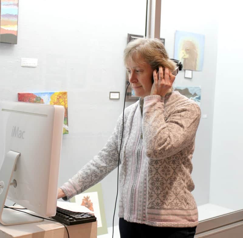 a woman using a computer in front of artwork