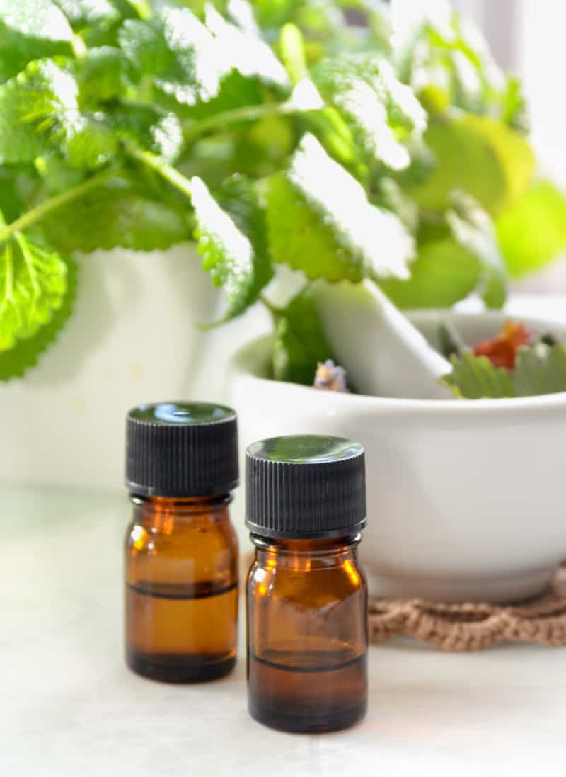 Brown essential oil bottles in front of a green plant