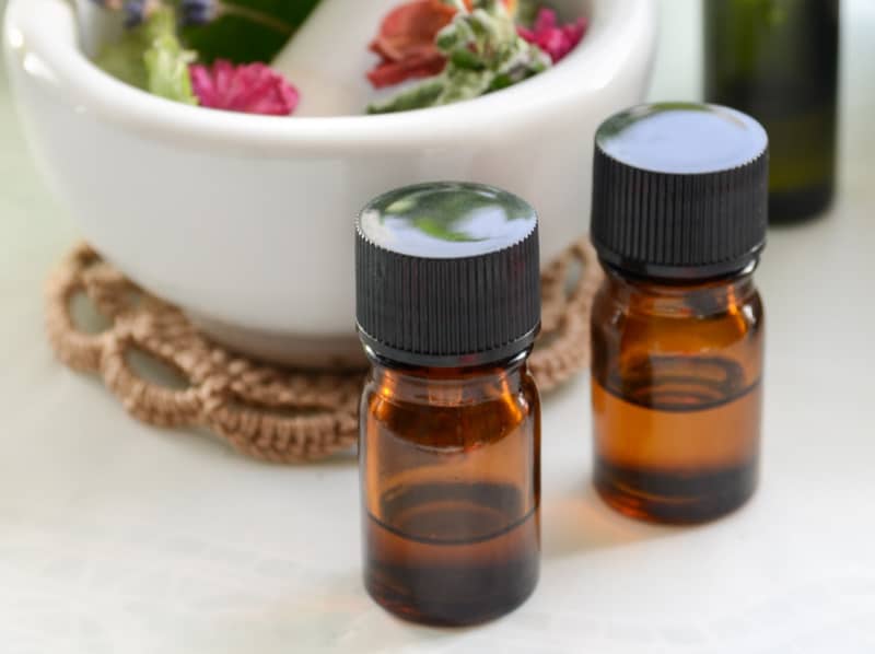 brown bottles near a white mortar and pestle with herbs