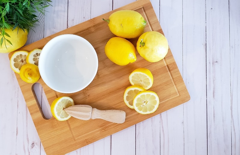 fresh cut lemons on a cutting board with a reamer