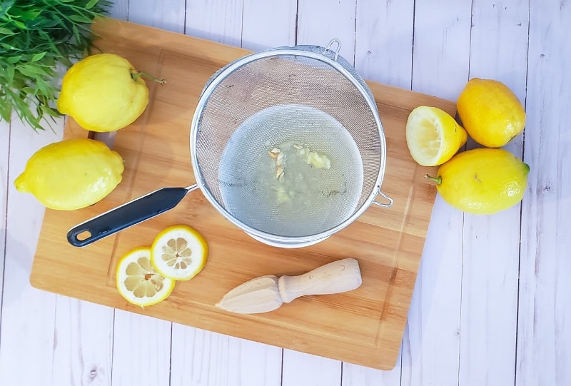 straining lemon juice through a sieve
