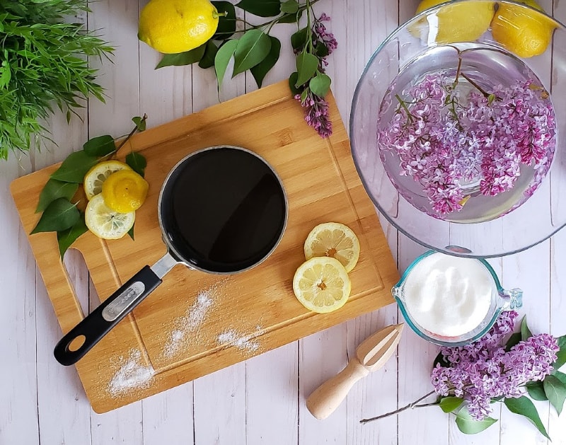 lilacs floating in water with sliced lemons on a cutting board