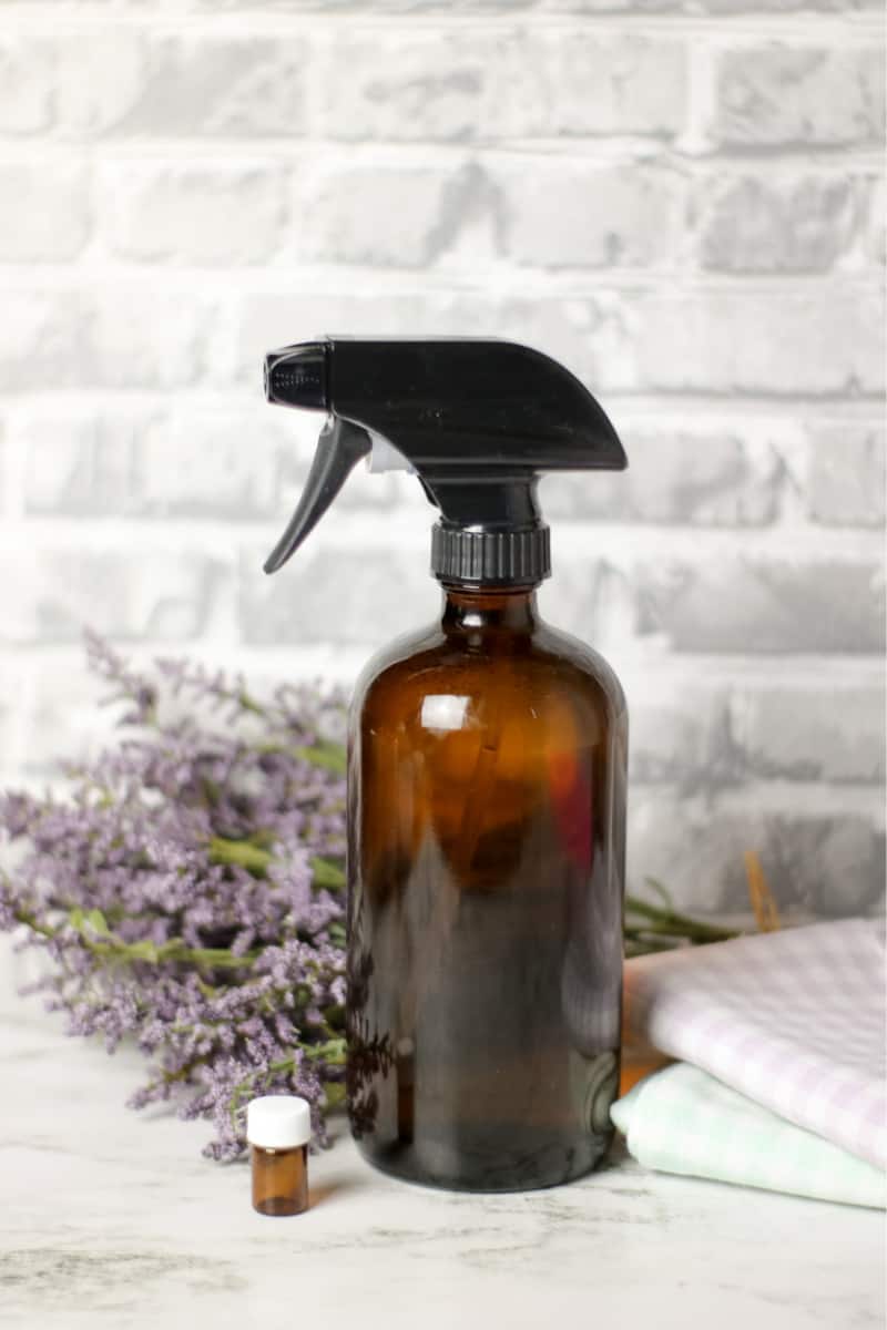 DIY dusting spray in a brown bottle with lavender on the counter