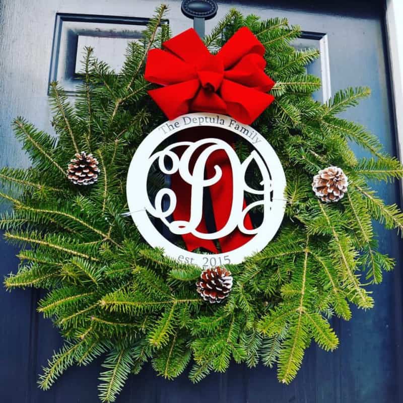 a wreath with a red bow and wooden cut out