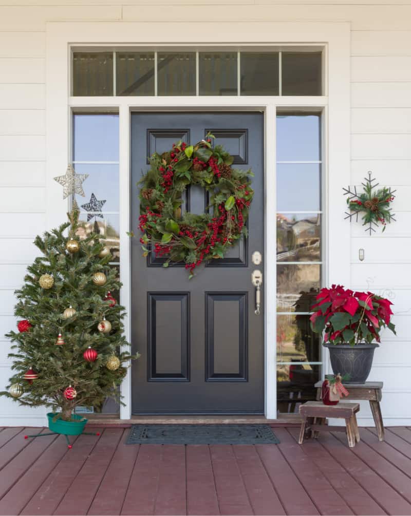 a front door decorated for winter with a wreath and fir tree in the front