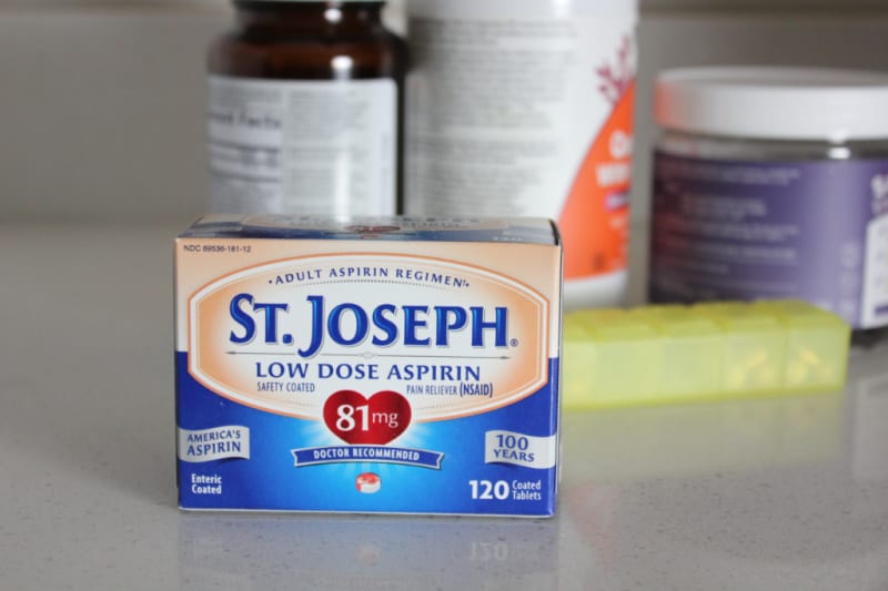 aspirin and supplements on a counter near a pill box