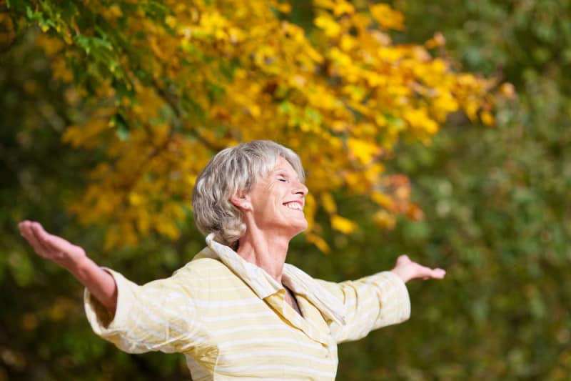 Senior woman with arms outstretched enjoying nature in park