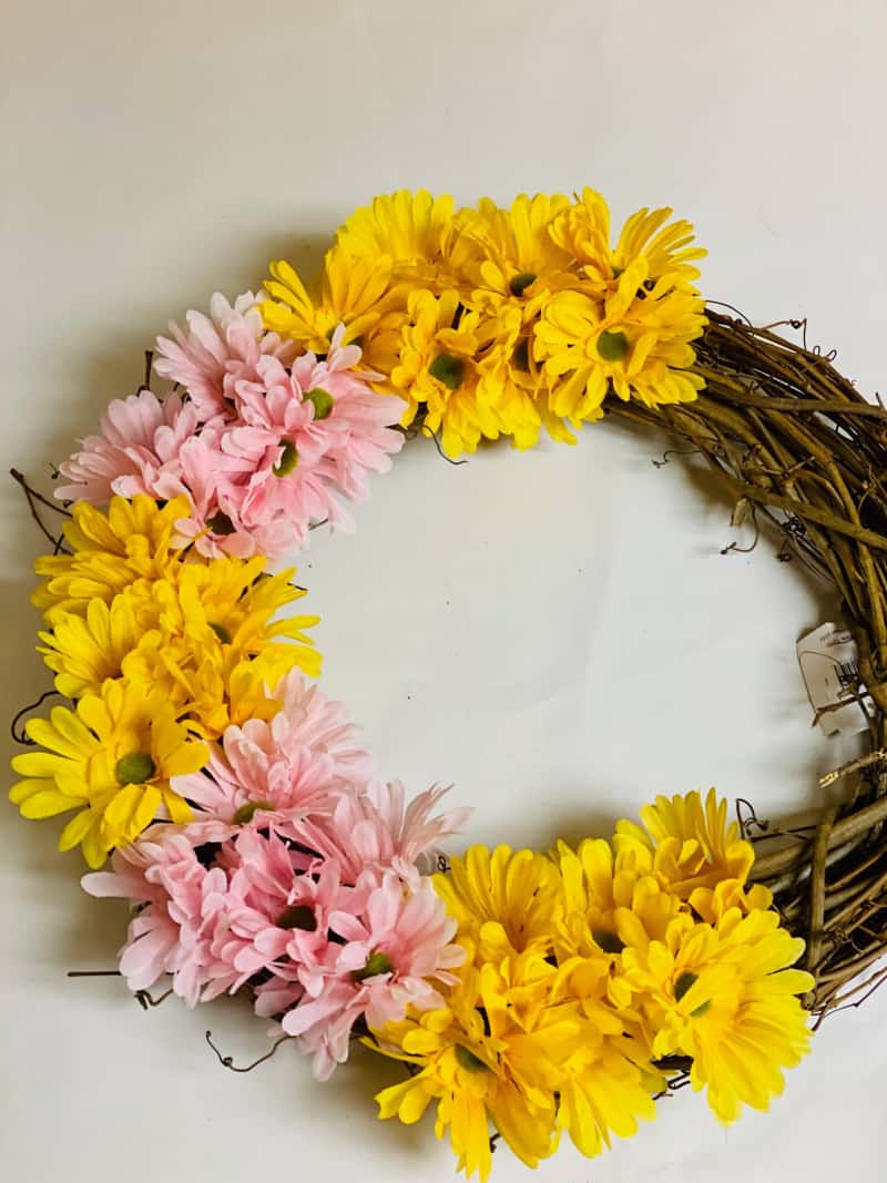 yellow and pink artificial flowers on a grapevine wreath
