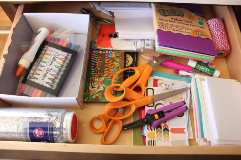 a disorganized drawer full of craft supplies