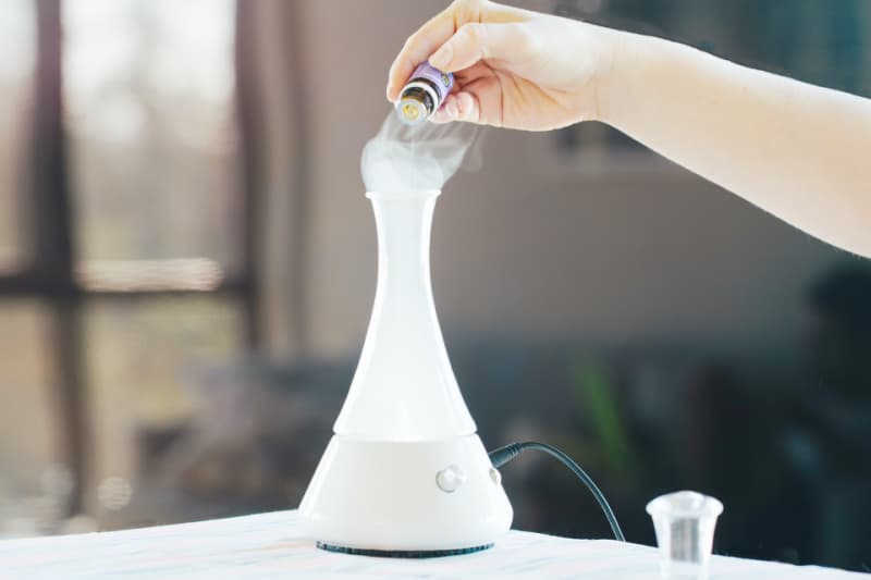 a woman adding essential oils to her diffuser