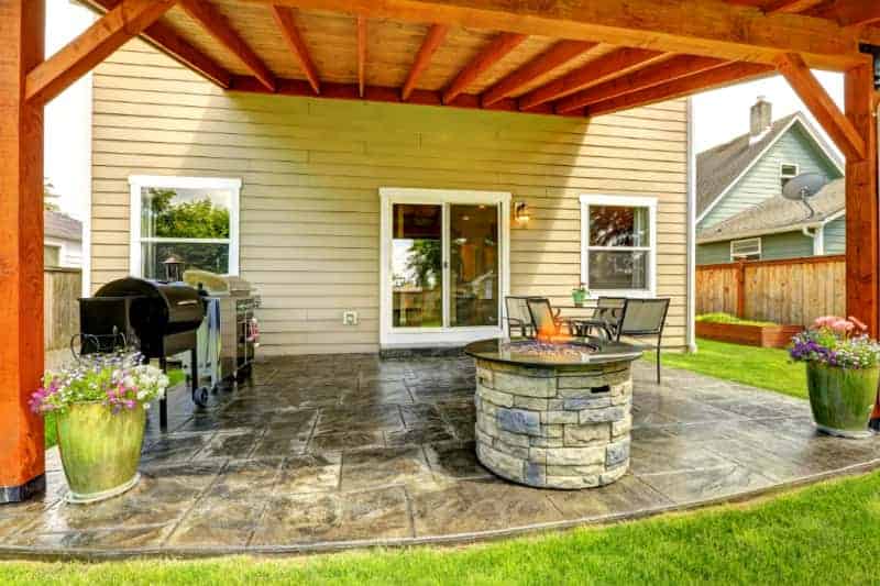 a patio with a propane fire pit, grill and patio furniture