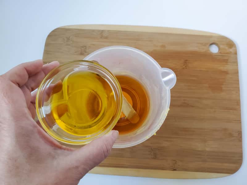pouring dandelion oil into a measuring cup