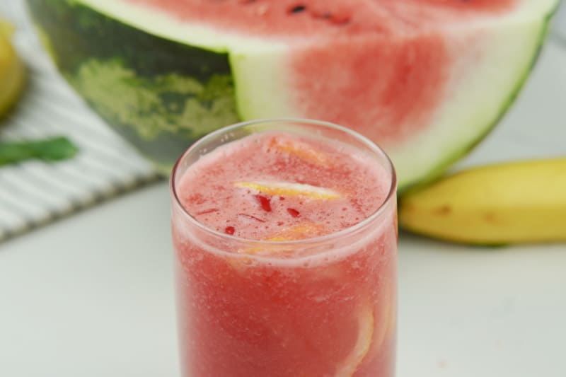 a glass full of watermelon drink with lemon