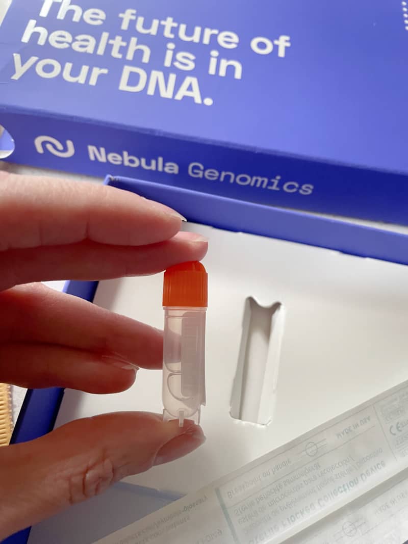 a woman holding a vial that is part of an at home DNA sequencing kit