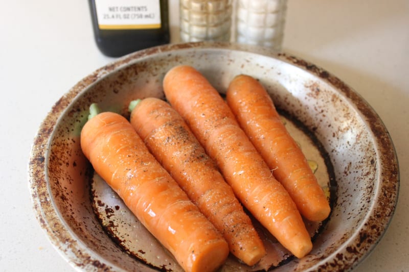 carrots in a metal dish with olive oil and seasoning