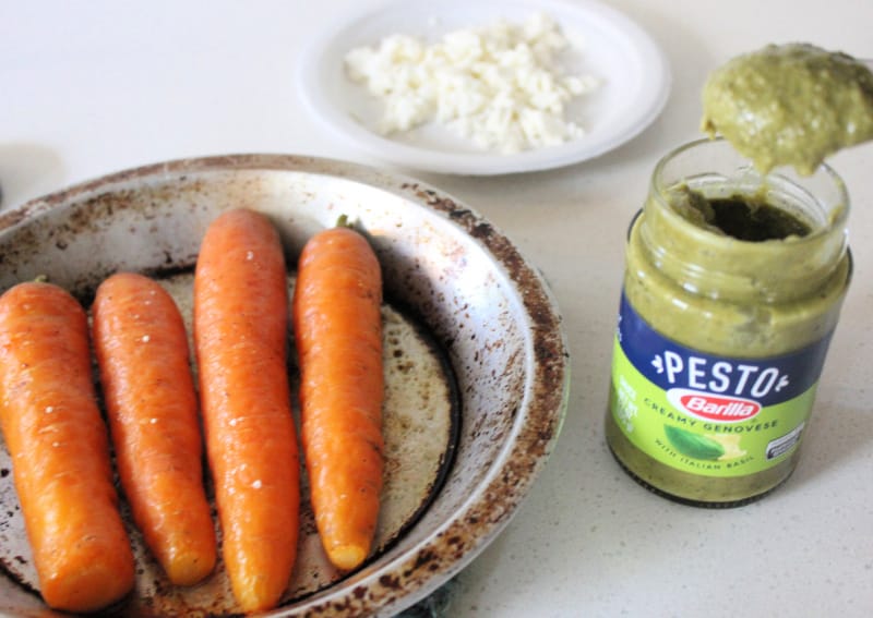 a jar of creamy pesto next to a pan of carrots
