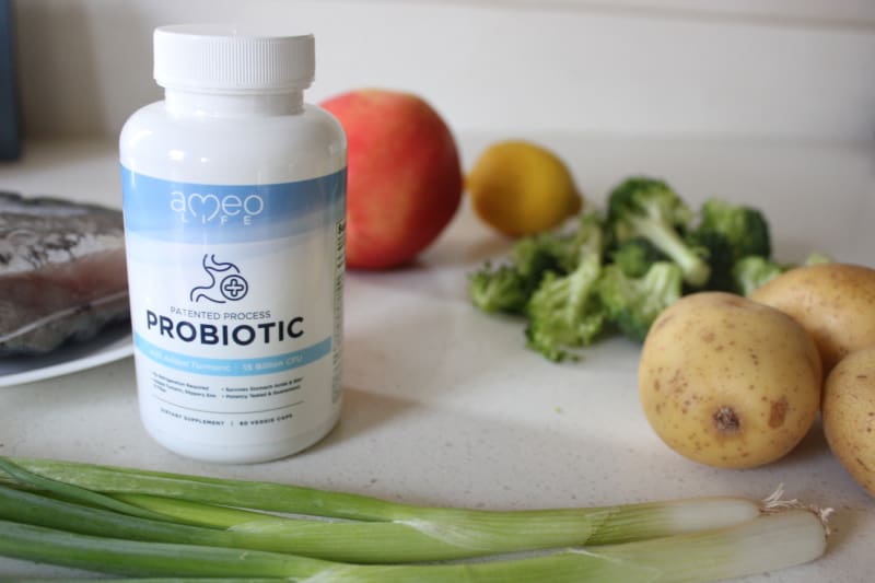 a probiotic in front of healthy food on the counter