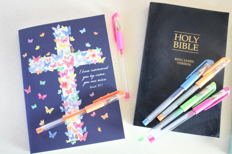 a Bible, pens, and a notebook on a white background