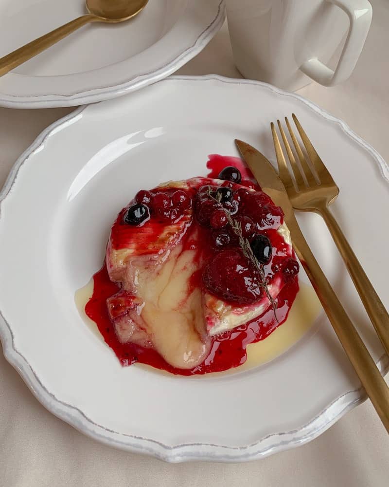melted brie with berry jam on a white plate