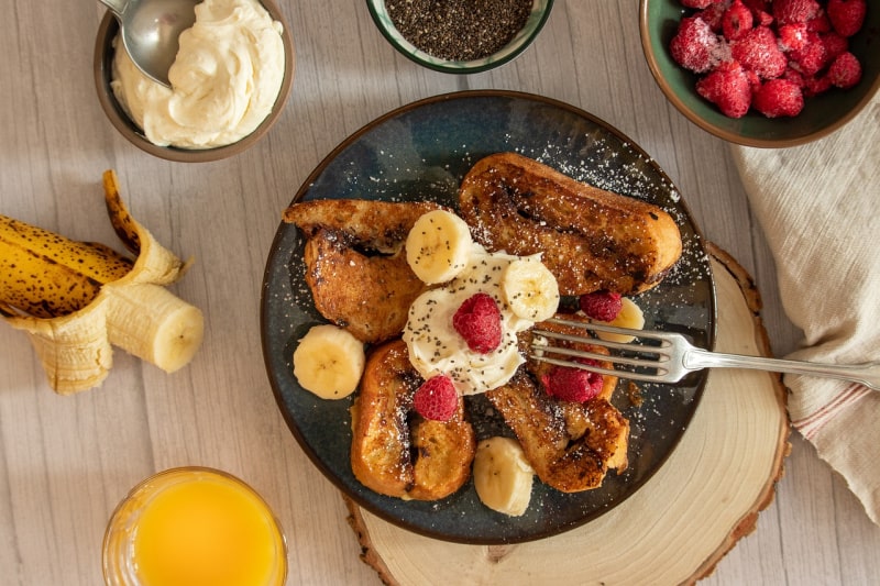 a plate of French toast with fruit and butter