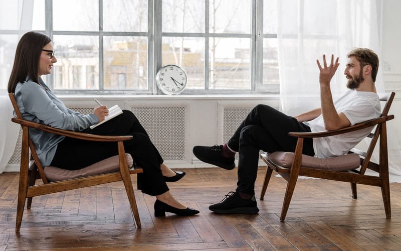 a man and woman sitting in chairs talking