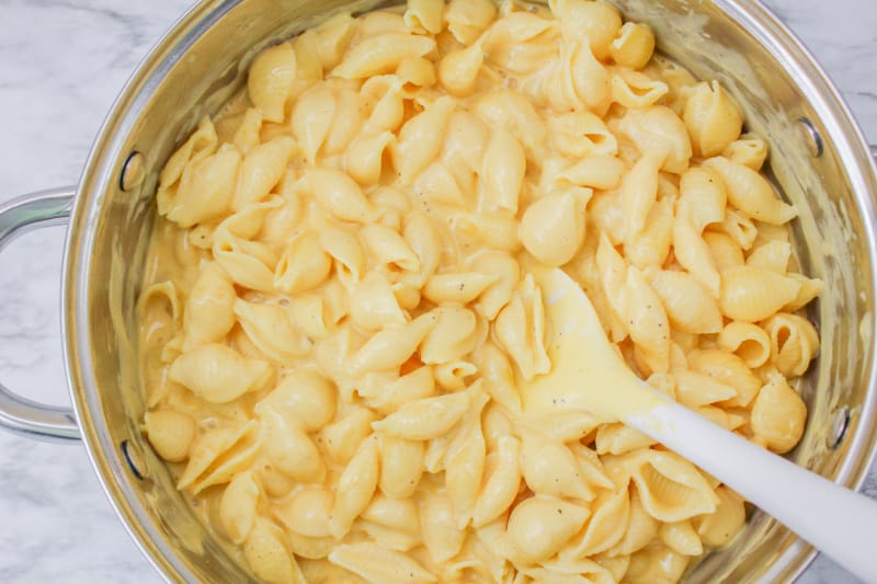 stirring pasta and cheese in a bowl