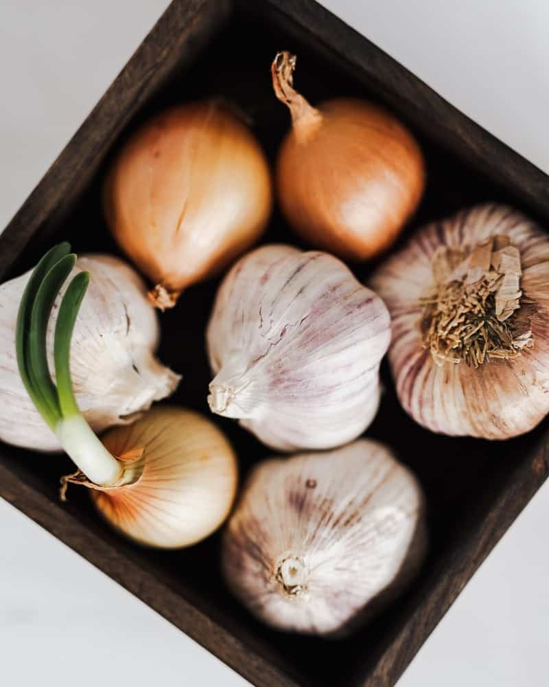 a bowl with onion and garlic bulbs