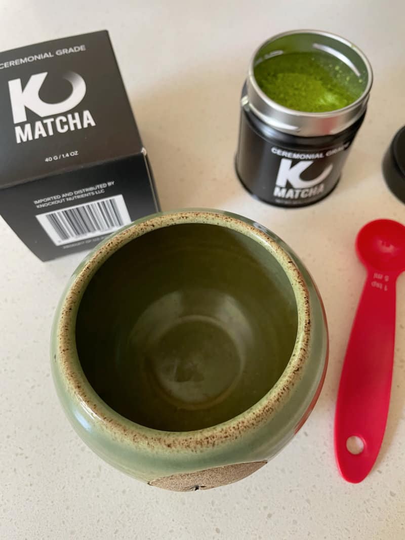 a small oriental cup and a tin of matcha