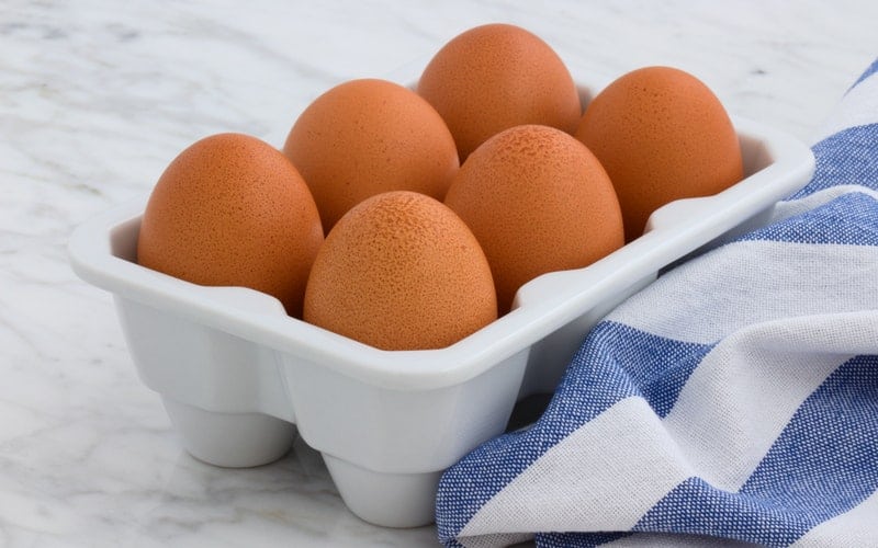 a carton of eggs on the counter with a towel