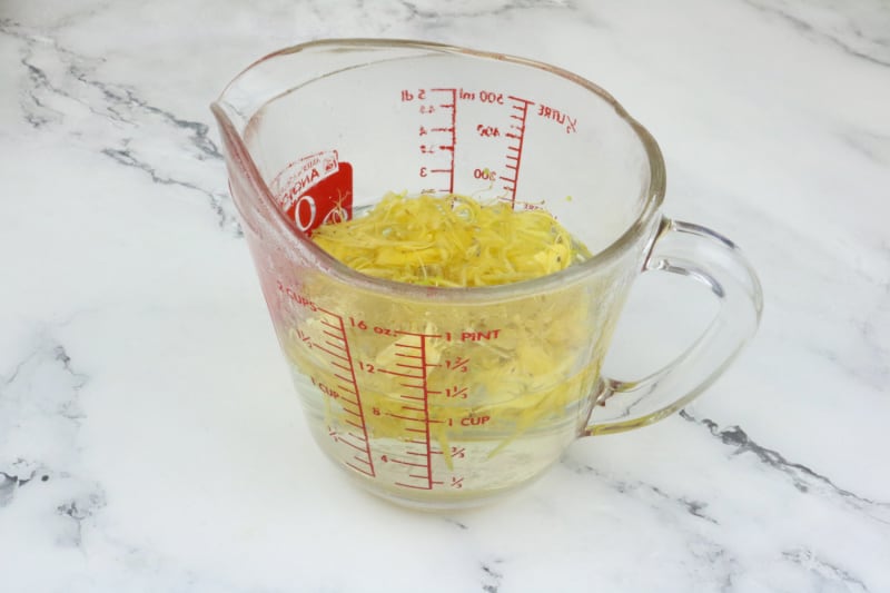 yellow flowers and water in a glass measuring cup