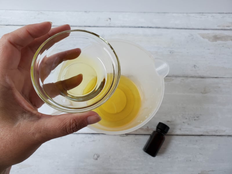 a hand holding a small glass bowl of oil