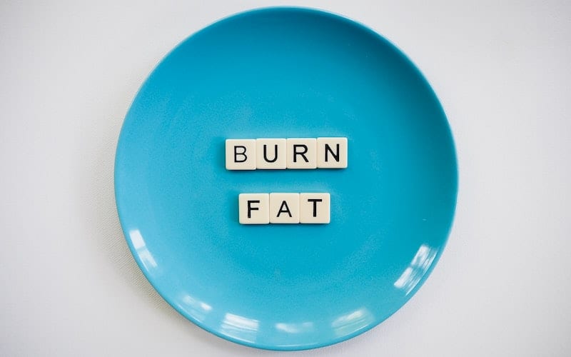 a blue plate with scrabble tiles that spell burn fat