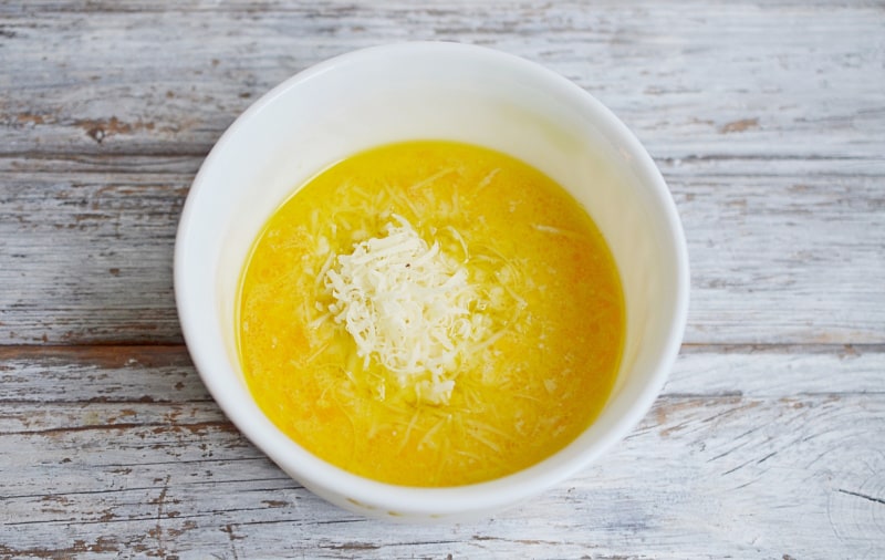 a white bowl with cheese and yellow liquid
