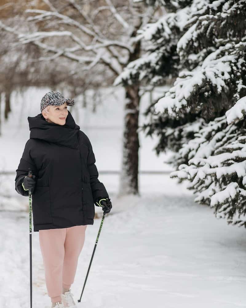 a woman walking in the snow with walking sticks