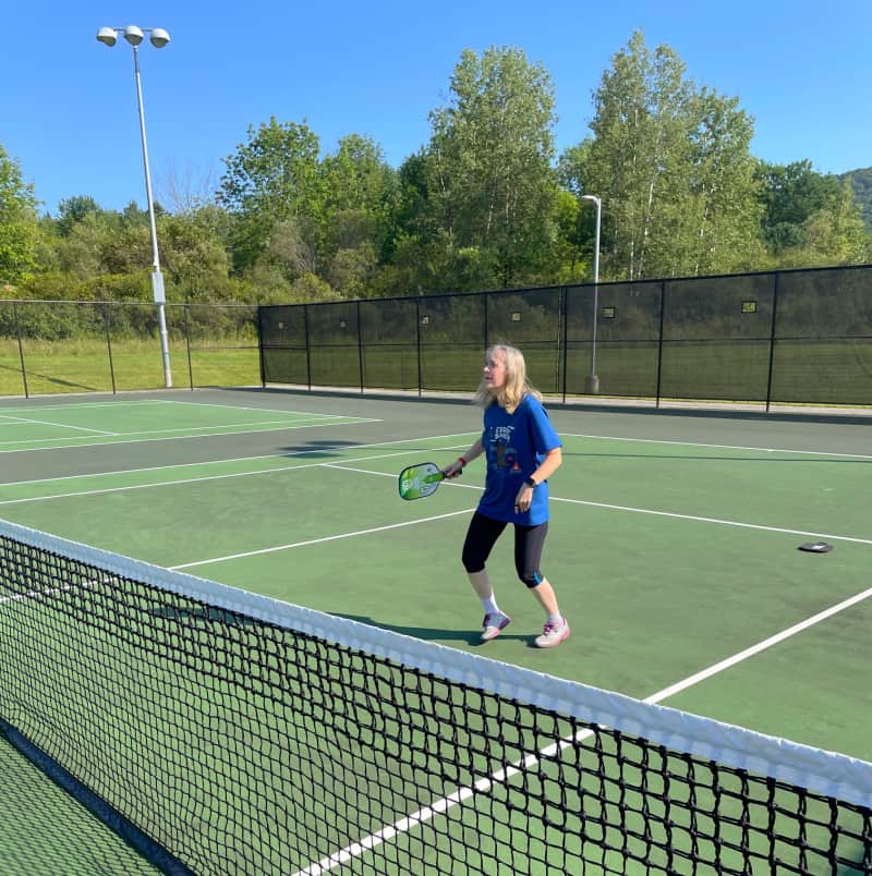 woman standing on a pickleball court with a paddle