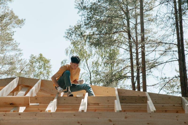 worker seated on wooden trusses
